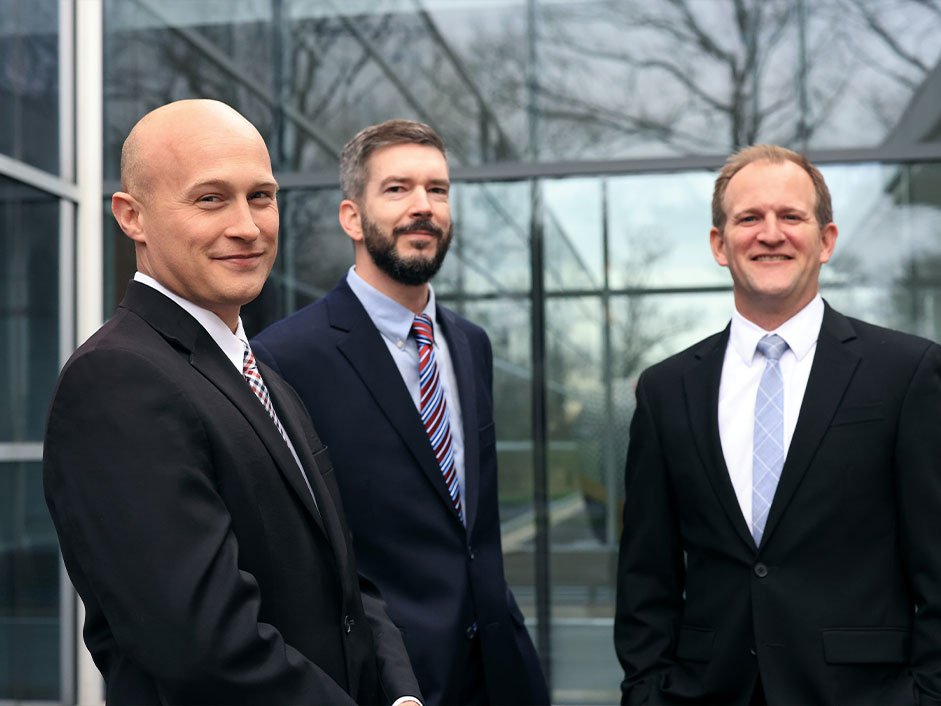 Three Hassakis and Hassakis attorneys outside a glass-fronted building